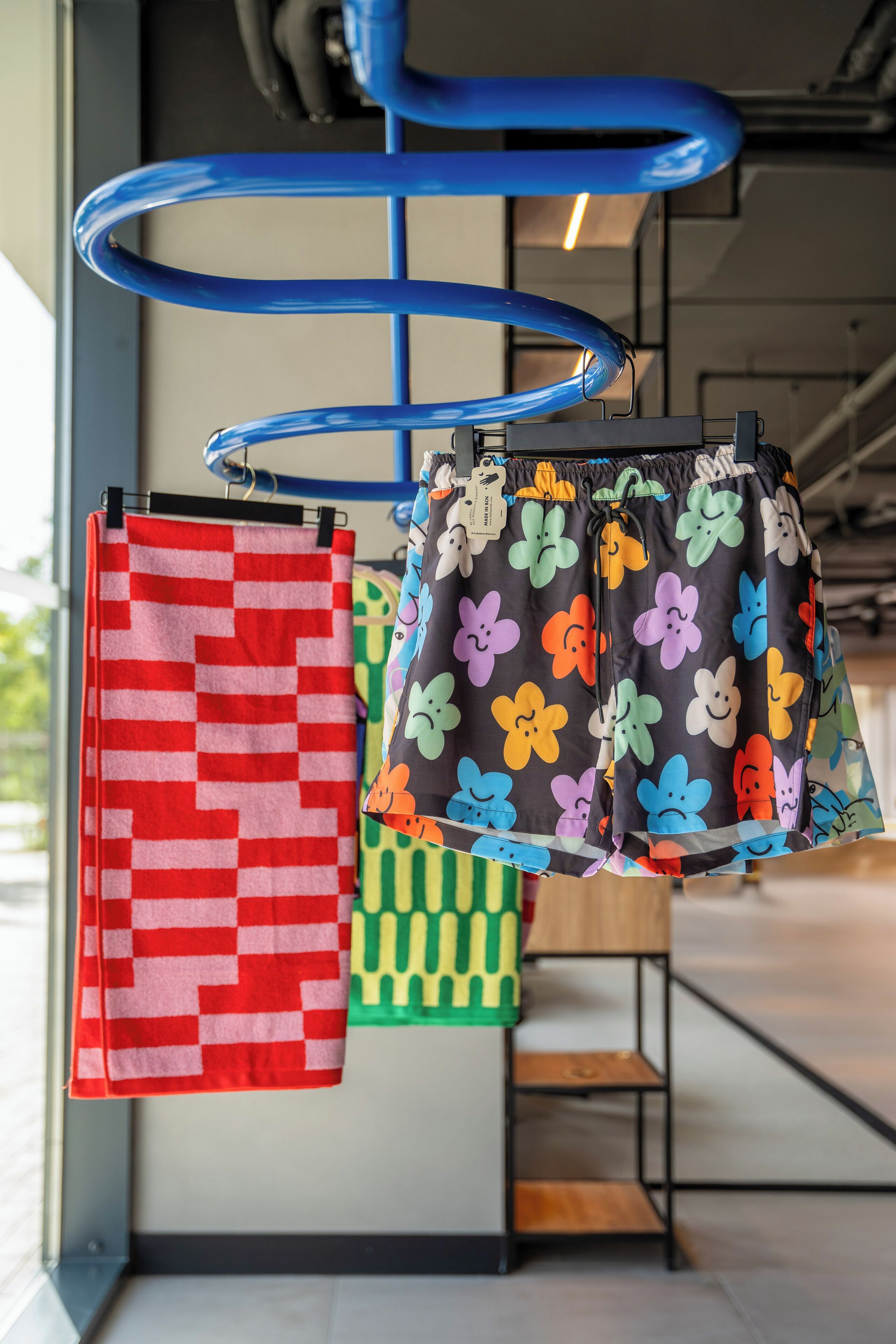 A rack with various patterned towels and shorts.