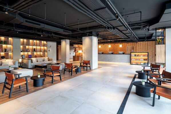 A modern lobby with a seating area, a reception desk, and a display of books and decorative items.