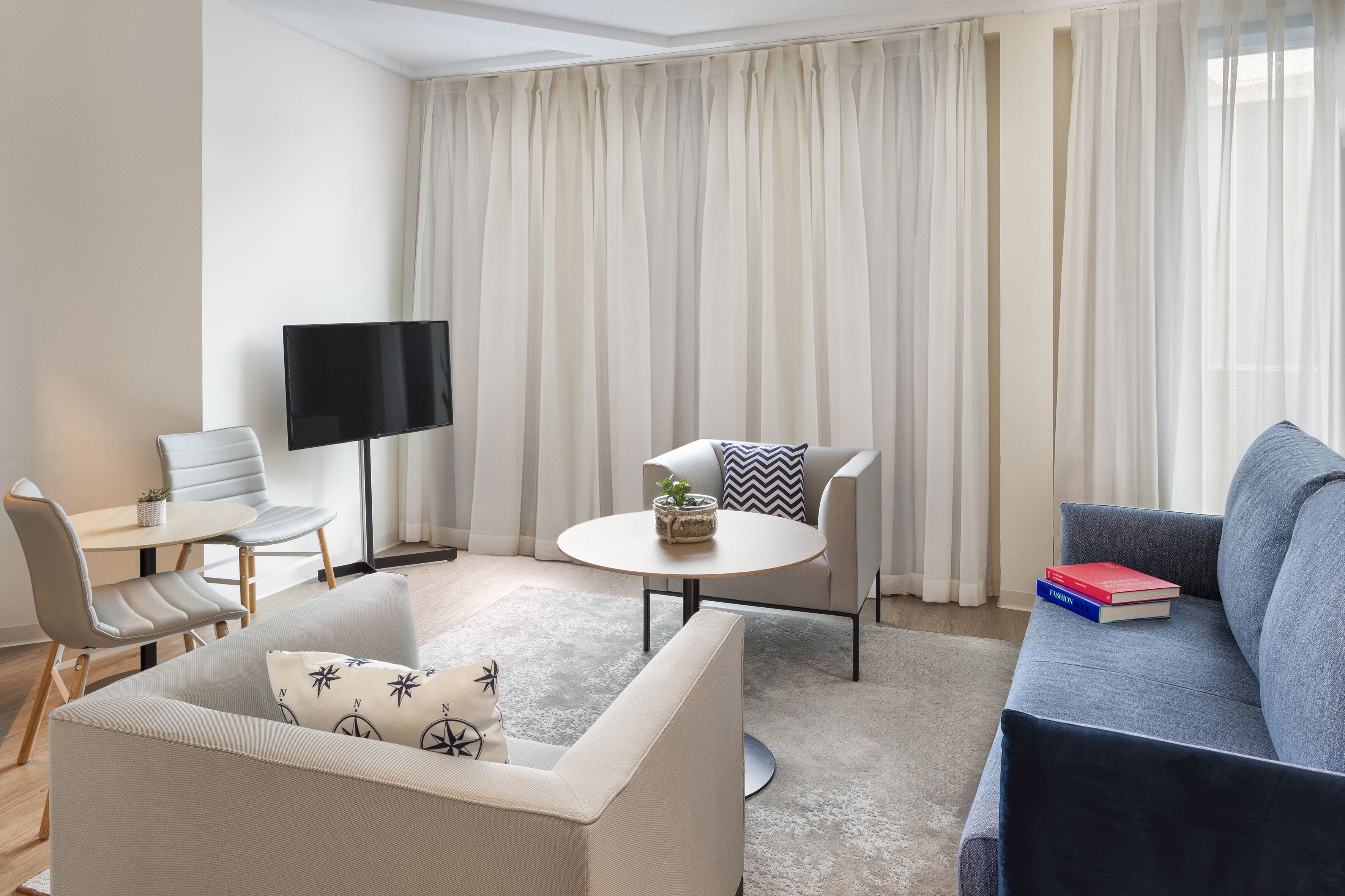 Una sala moderna con un sofá, una mesa de centro, un televisor y un comedor con una mesa y sillas.