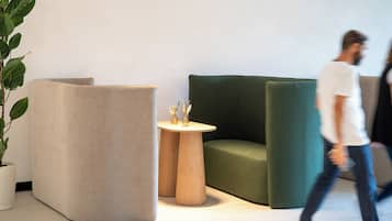 Un interior moderno con un sofá verde, un sillón beige y una pequeña mesa de madera con objetos decorativos.