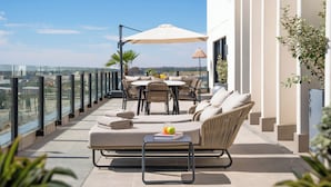 A rooftop terrace with a sofa, dining table, and chairs, overlooking a cityscape. - INNSiDE by Meliá Madrid Valdebebas (Madrid)