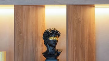 Una estantería con libros, un busto y una lámpara.