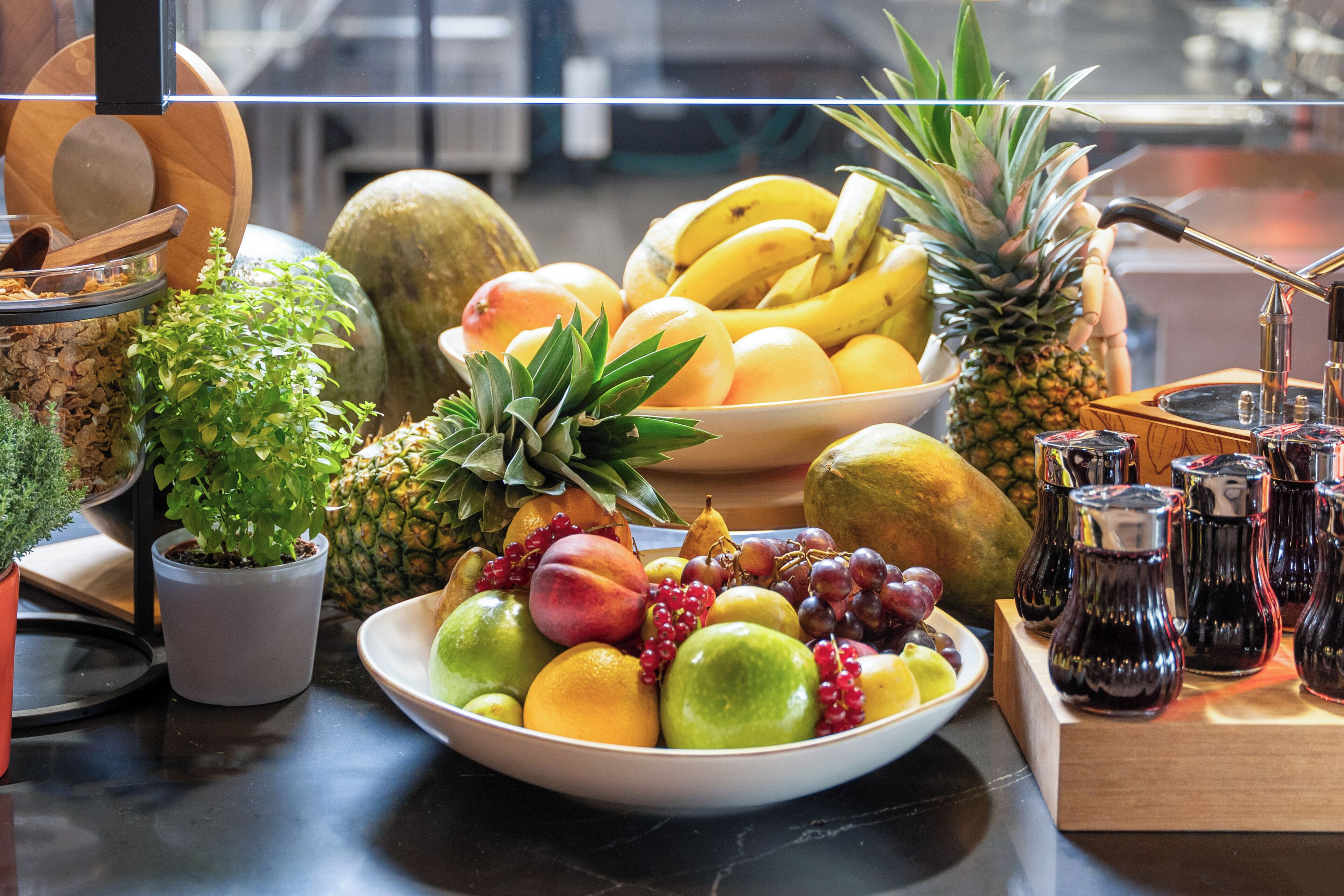 Un frutero con diversas frutas y una planta en maceta.