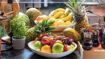 Un frutero con diversas frutas y una planta en maceta.