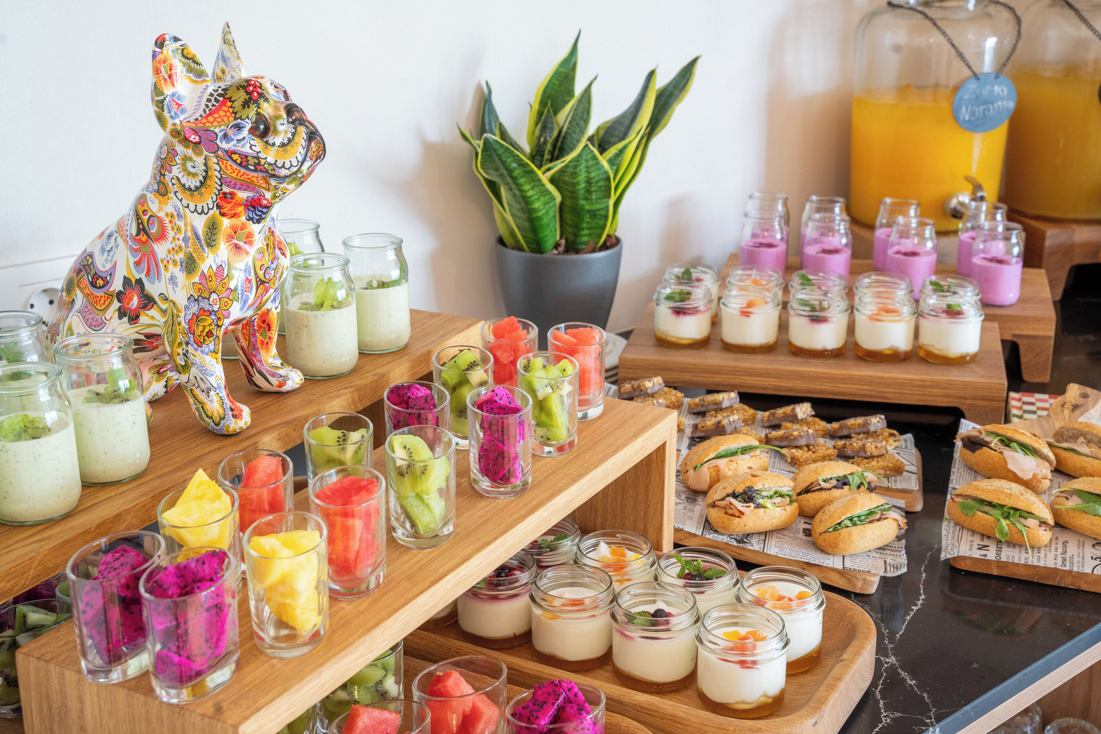 A buffet with various food items, including fruit cups, desserts, and sandwiches.
