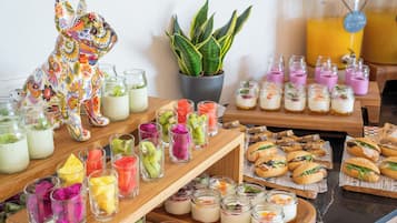 A buffet with various food items, including fruit cups, desserts, and sandwiches.