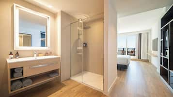 Un baño moderno con ducha de vidrio, un espejo grande y tocador con toallas.