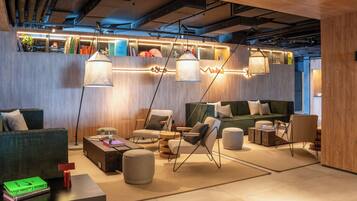 A modern lounge area with seating, tables, and hanging lights.