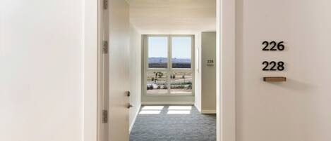 A hallway with a carpeted floor leading to a door marked with numbers 226 and 228.