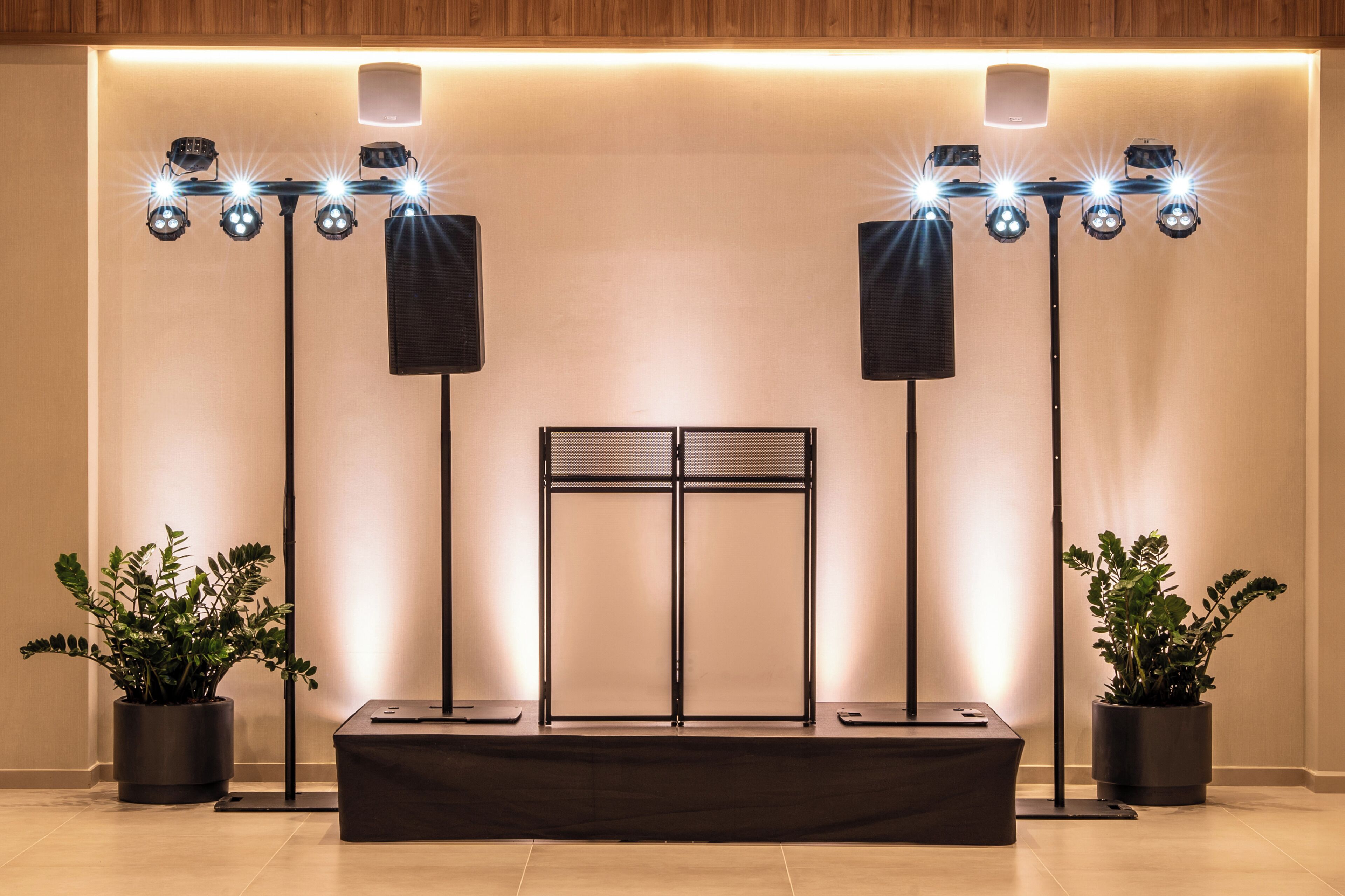 A stage with a black backdrop, two speakers, and a row of spotlights.