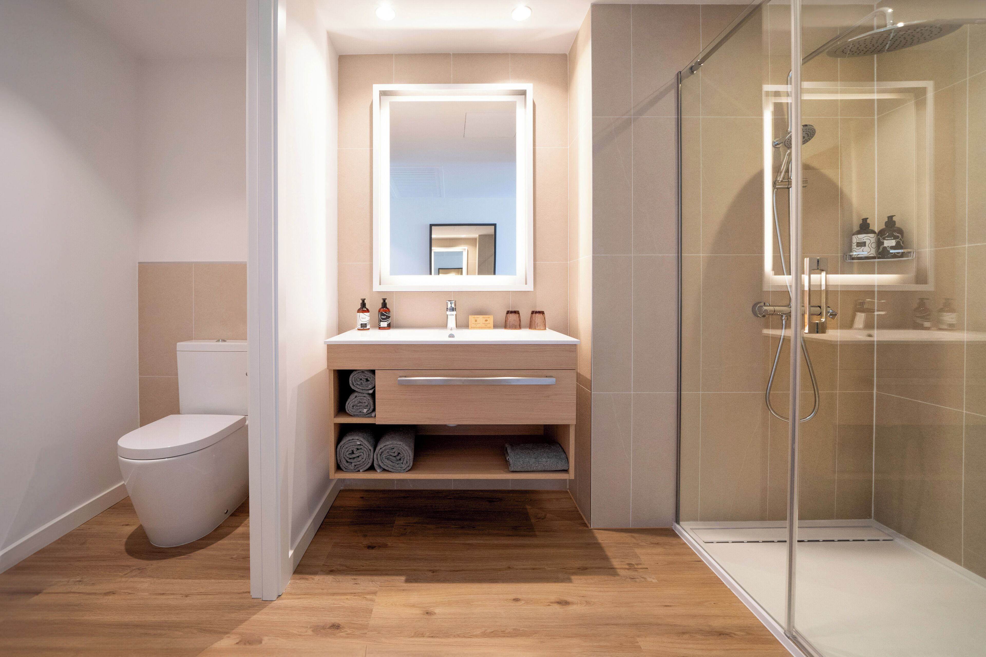 A modern bathroom with a toilet, a sink with a mirror, and a glass shower enclosure.