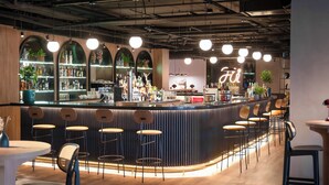 A modern bar area with a curved counter, multiple stools, and a neon sign. - INNSiDE by Meliá Madrid Valdebebas (Madrid)