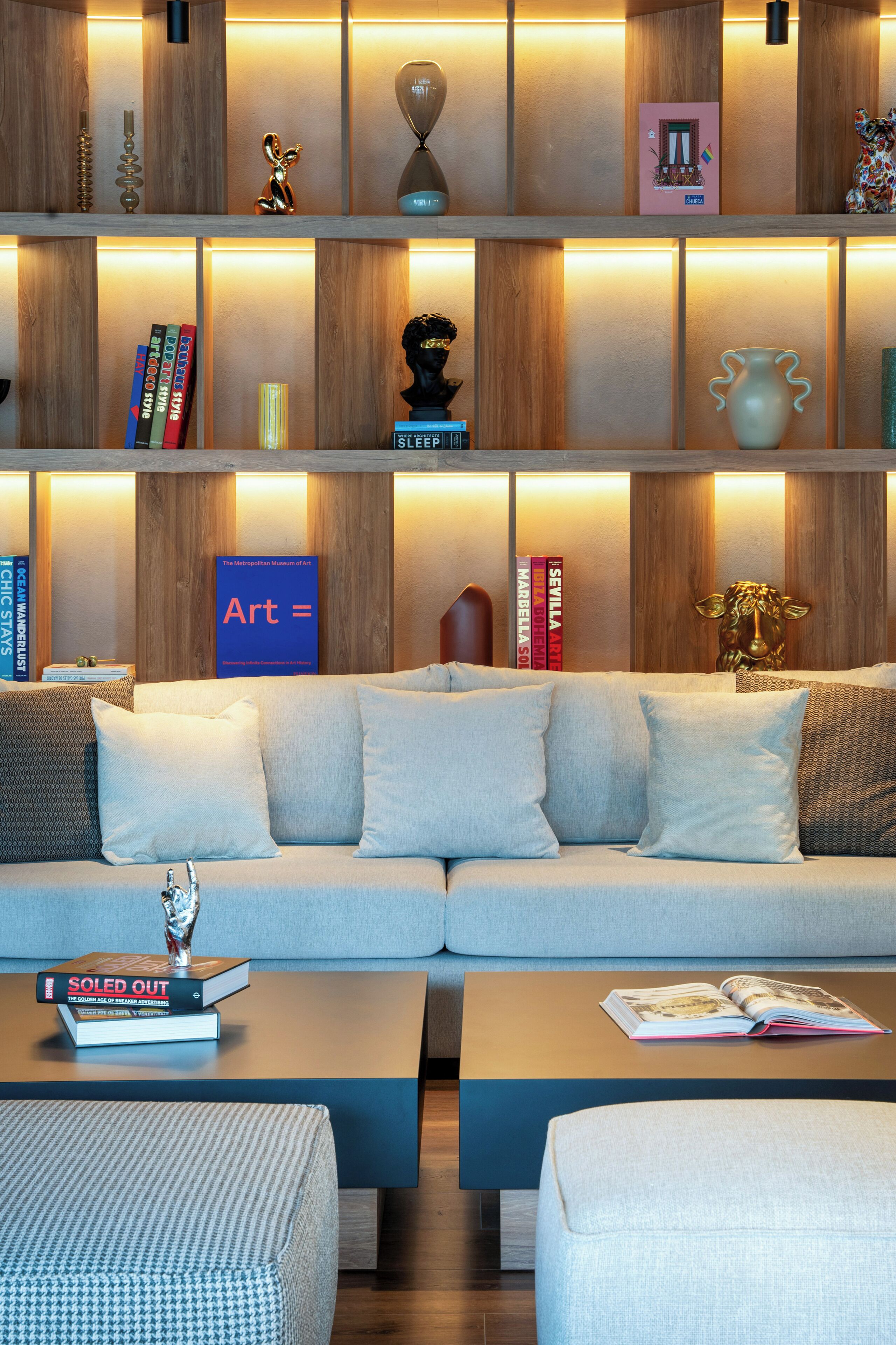 A modern living room with a sectional sofa, a coffee table, and a bookshelf filled with books and decorative items.