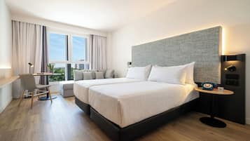 Een moderne hotelkamer met twee bedden, een bureau en uitzicht op de stad.
