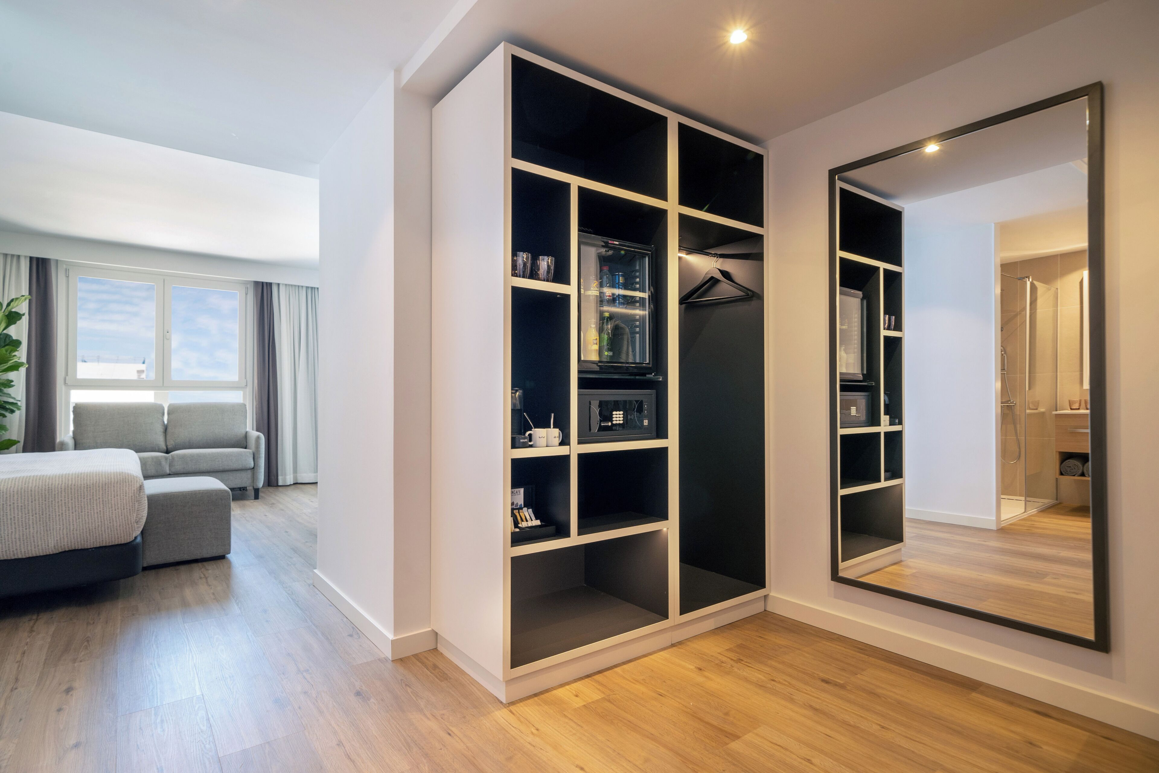 Un dormitorio moderno con un armario grande, una cama, un sofá y un espejo.