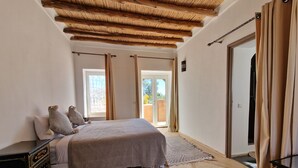 A bedroom with a bed, a nightstand, a patterned rug, and a wooden ceiling. - Manzal Lahbab (Marrakech)