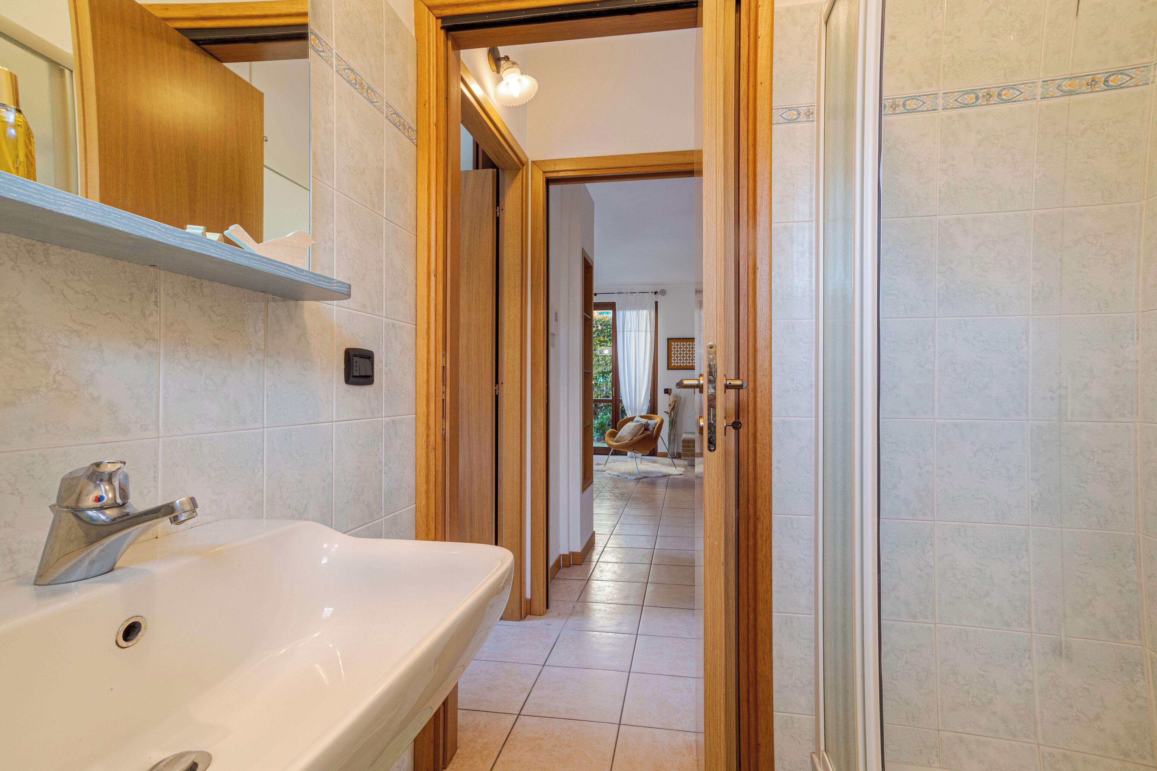 A bathroom with a white sink, wooden door, and tiled floor.