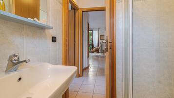 A bathroom with a white sink, wooden door, and tiled floor.