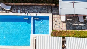 Une piscine bordée et entourée d’un muret en pierre.