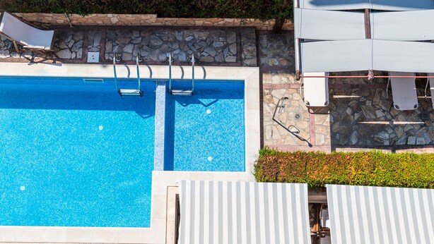 A swimming pool with a stone border and a stone wall. - Afrodita 2 (Nessebar)