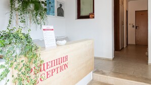 A reception area with a wooden desk, a sign reading "RECEPTION," and a staircase leading to another part of the building. - Afrodita 2 (Nessebar)