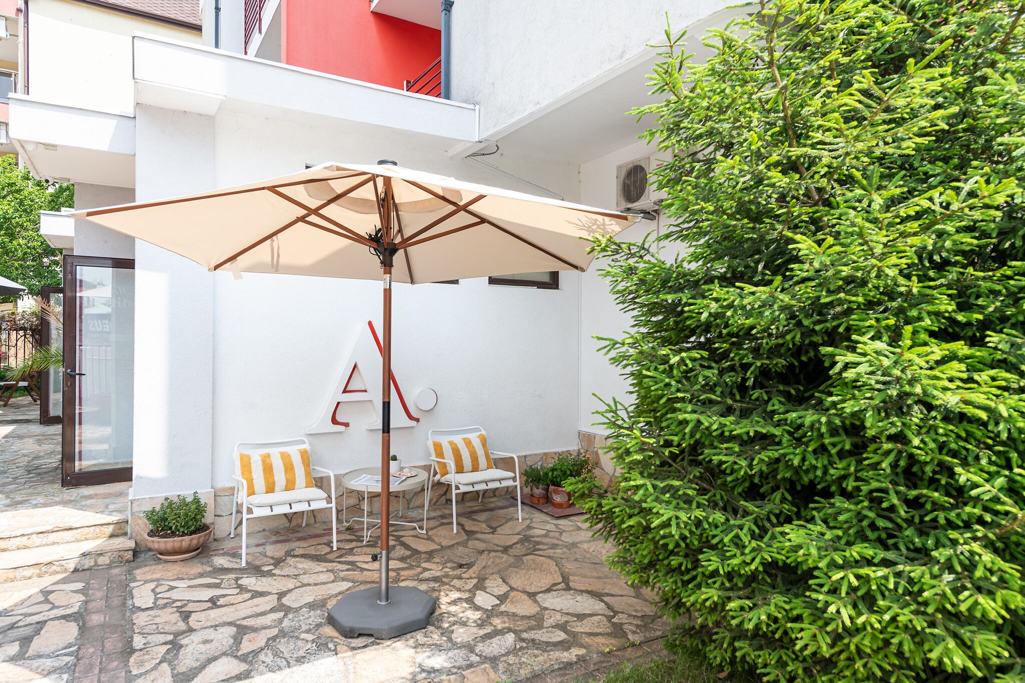 A patio area with a table and chairs, a large umbrella, and potted plants.