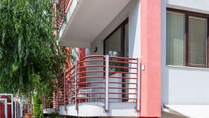 A multi-story building with a stone-paved courtyard, a red metal railing, and potted plants. - Afrodita 2 (Nessebar)