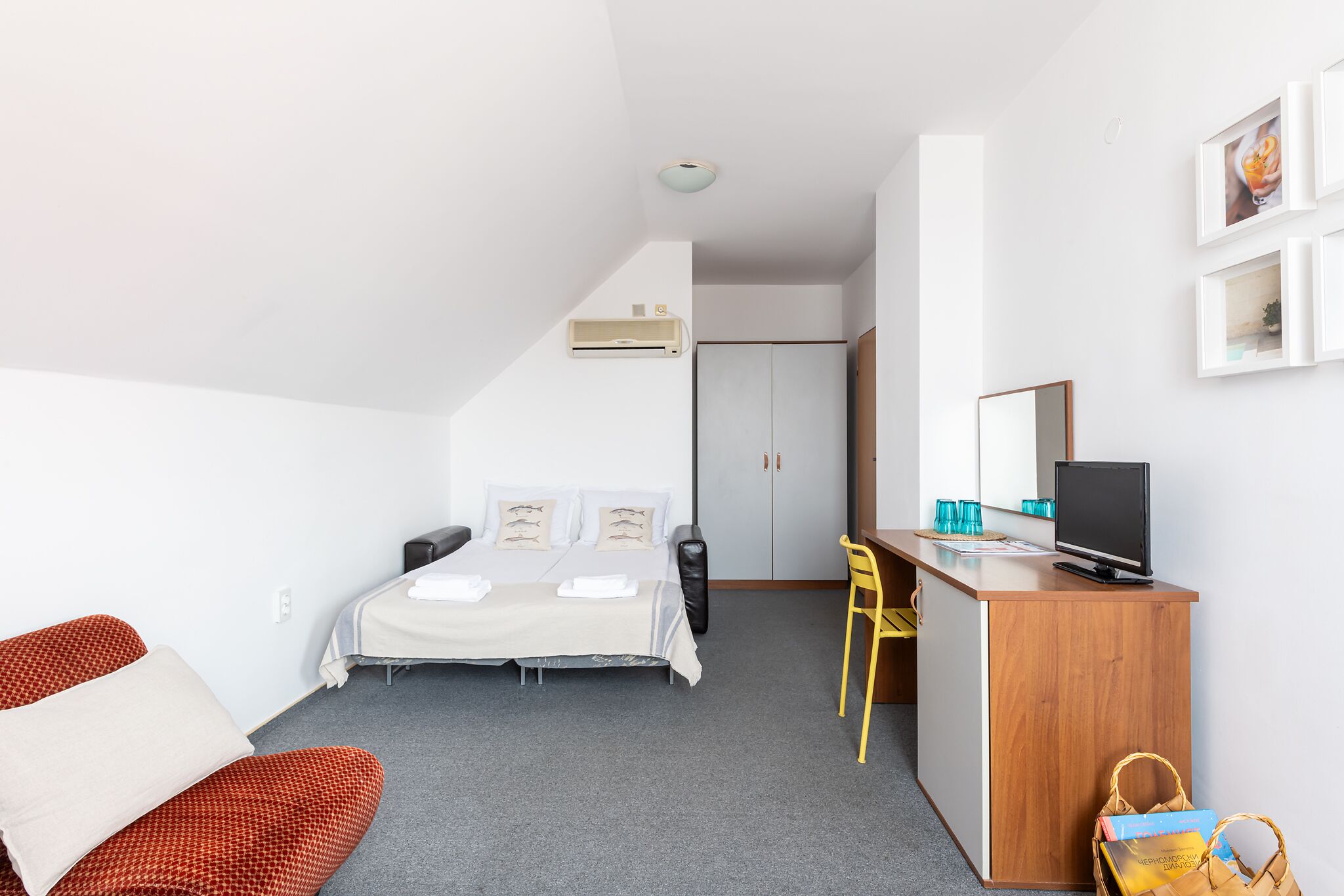 A hotel room with a bed, a desk, a chair, and a television.