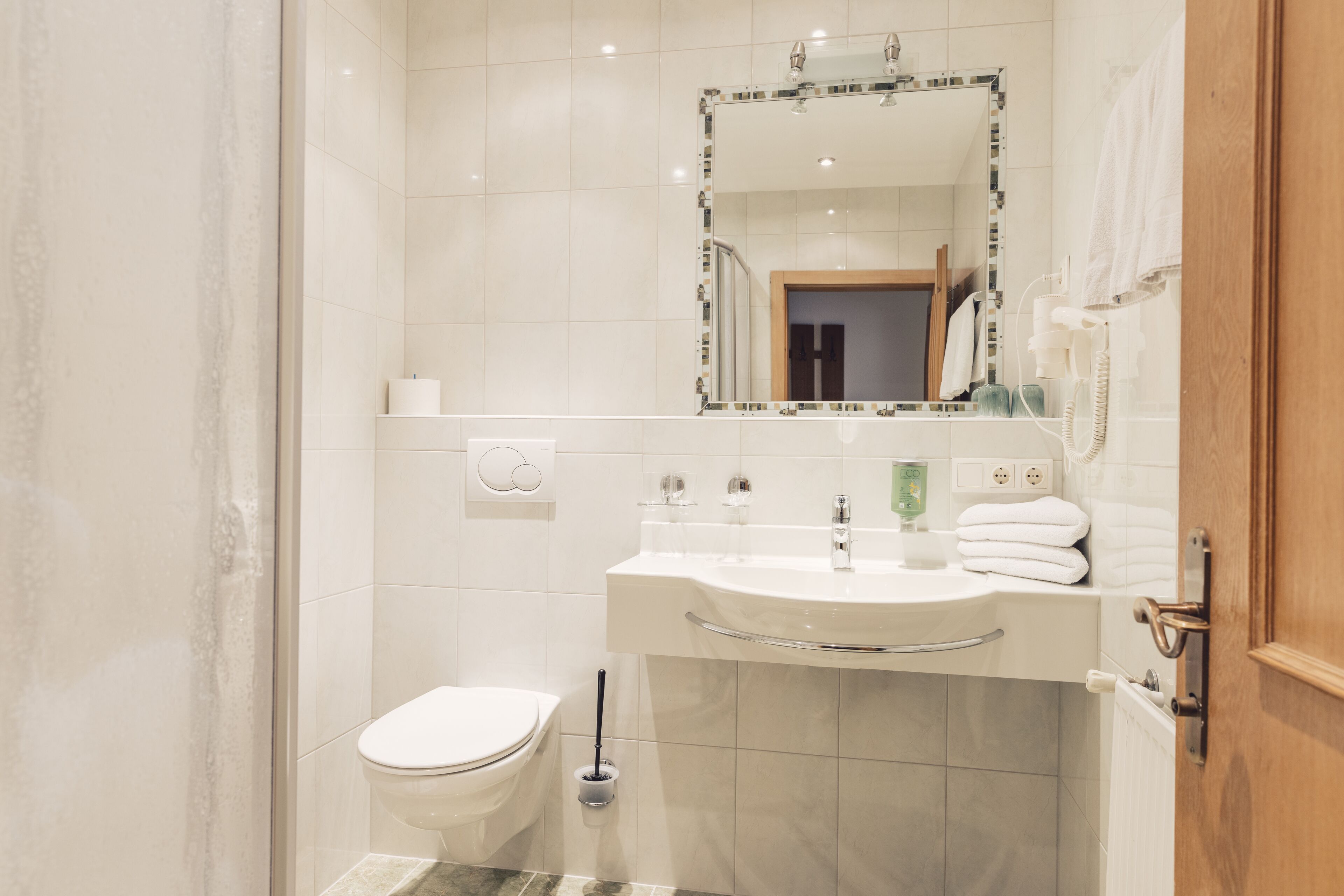 A modern bathroom with a toilet, sink, and mirror.