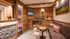 A cozy room with wooden walls, a fireplace, a sofa, and a stone wall. - Hotel Märzenklamm Stumm im Zillertal (Stumm)