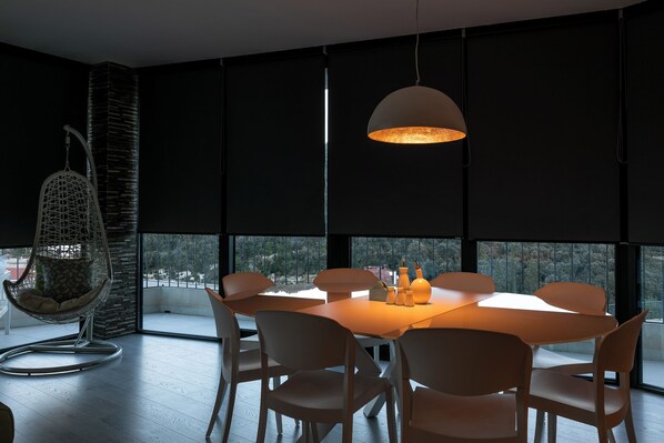 Un comedor moderno con una mesa redonda, seis sillas, una lámpara colgante y un sillón colgante.