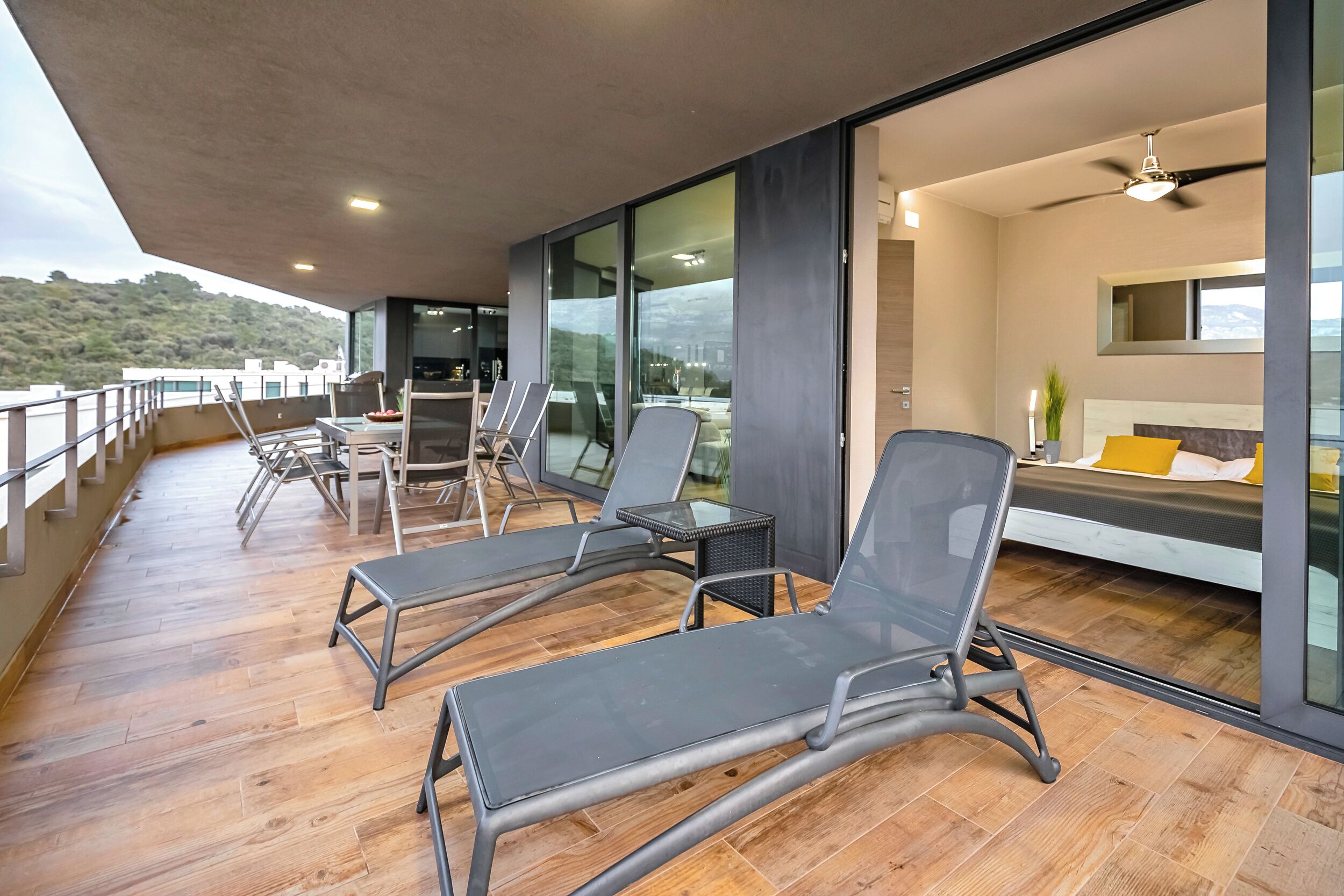 Een moderne kamer met balkon, grote ramen en een bed met uitzicht.