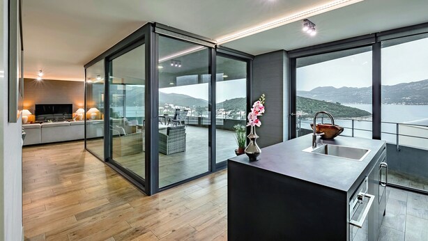 Una cocina moderna con una isla grande, horno empotrado y vistas al mar.