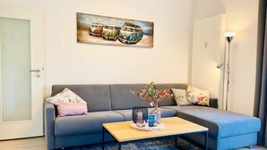 A modern living room with a grey sofa, a wooden coffee table, and a blue rug.