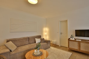 A living room with a sofa, a coffee table, a television, and a door.