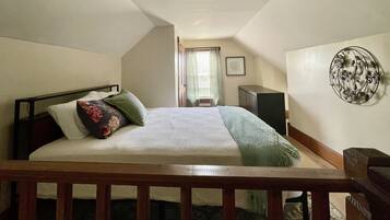 A bedroom with a bed, a dresser, a desk, and a window with curtains.