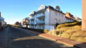 Une rue bordée d’immeubles à plusieurs étages, dont certains sont dotés de balcons.