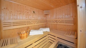Un sauna avec des bancs en bois et un seau en bois.