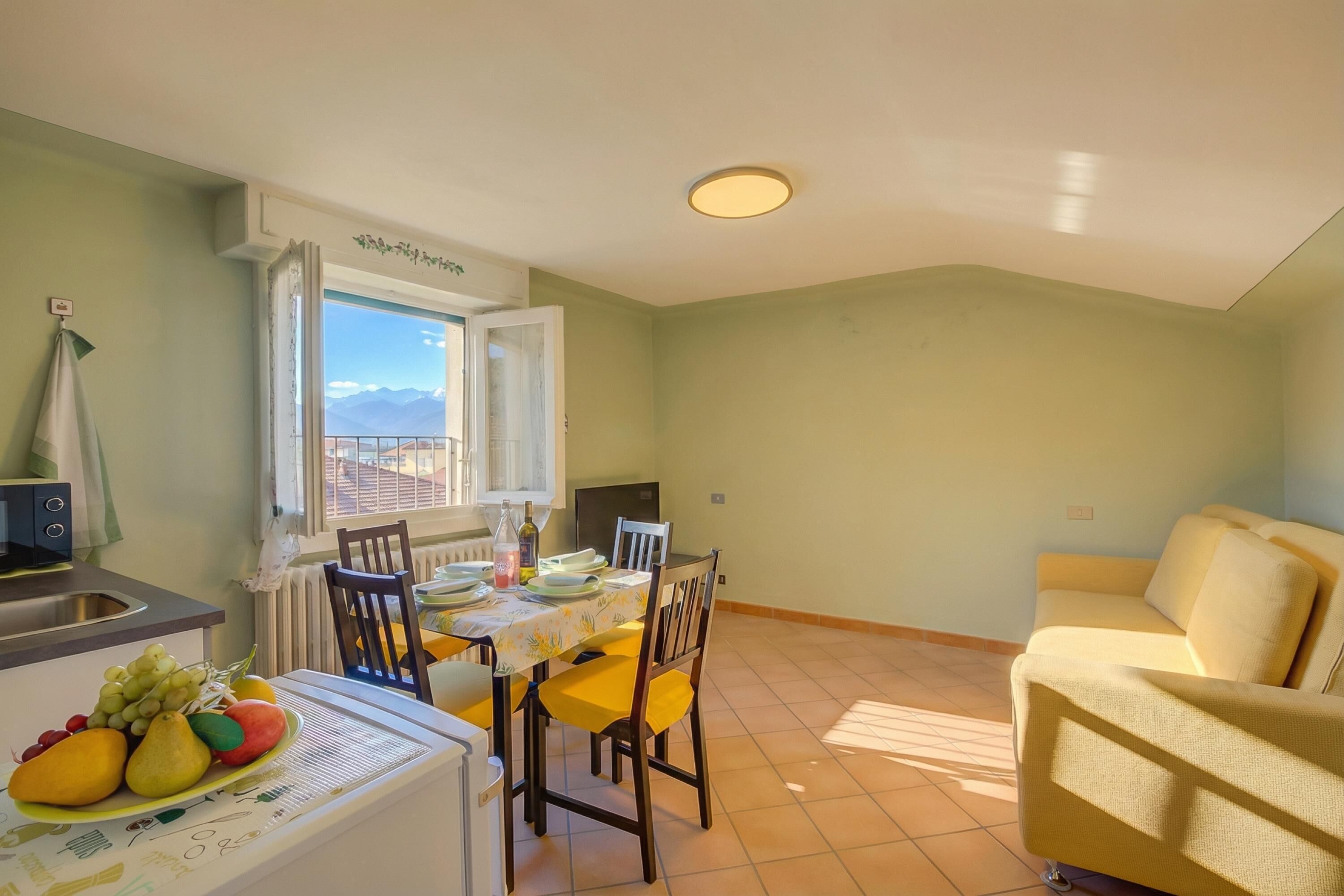 A dining area with a table set for four, a sofa, and a window with a view of mountains.
