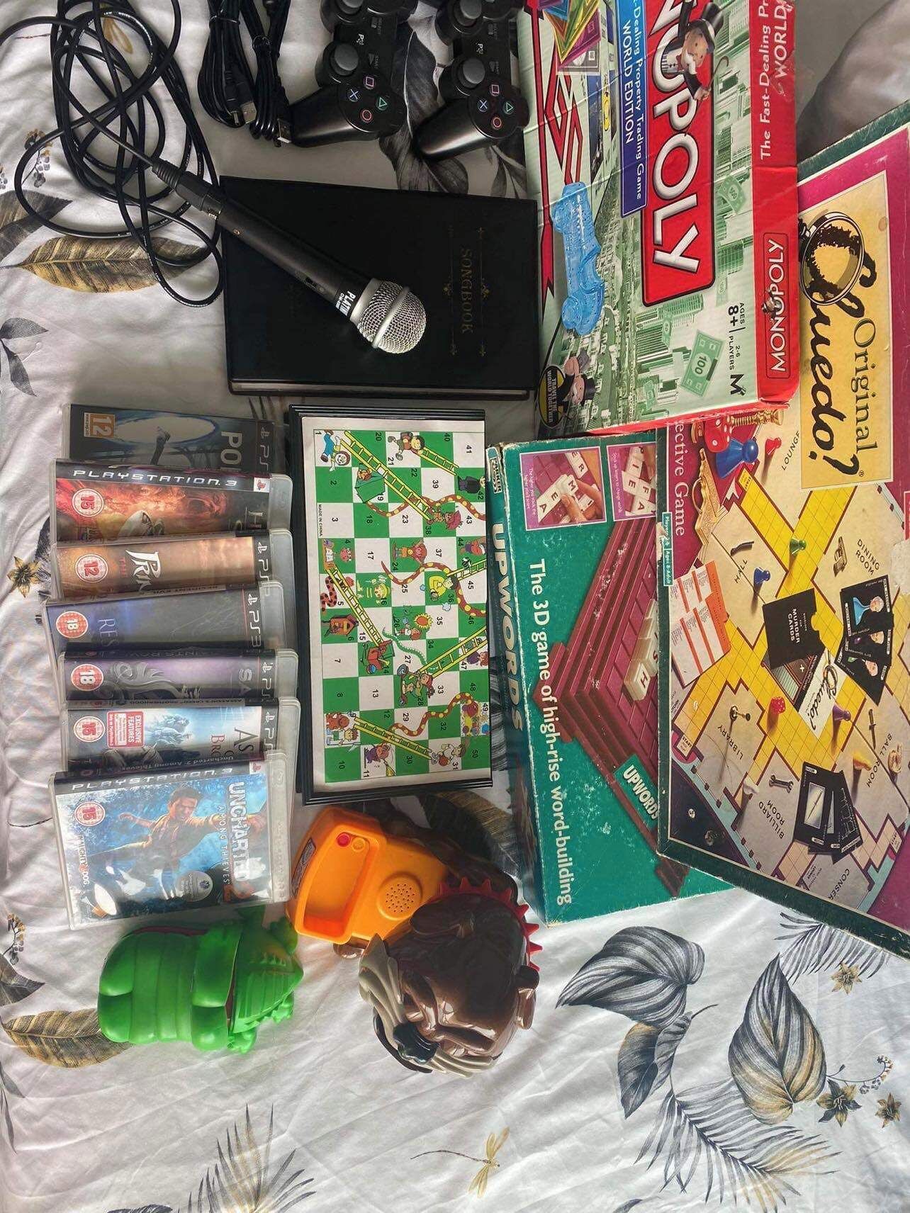A collection of board games, video games, and a microphone on a patterned surface.