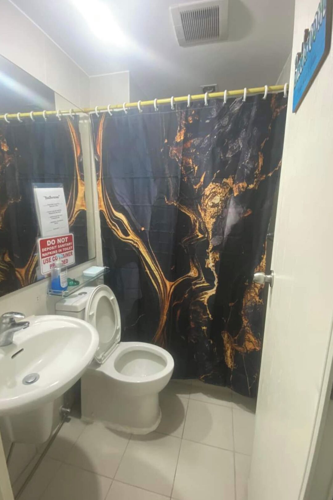 A bathroom with a marble-patterned shower curtain, a sink, and a toilet.