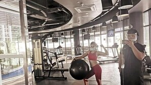 A gym with exercise equipment, a large window, and a person taking a selfie. - Azure 1BR Citylights With Netlfix Near Airport (Parañaque)