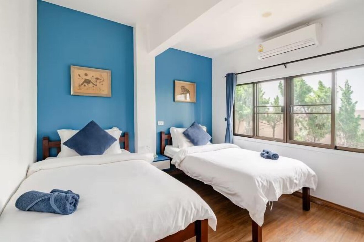 Une chambre d’hôtel avec deux lits, une fenêtre donnant sur un beau paysage et un tableau au mur.
