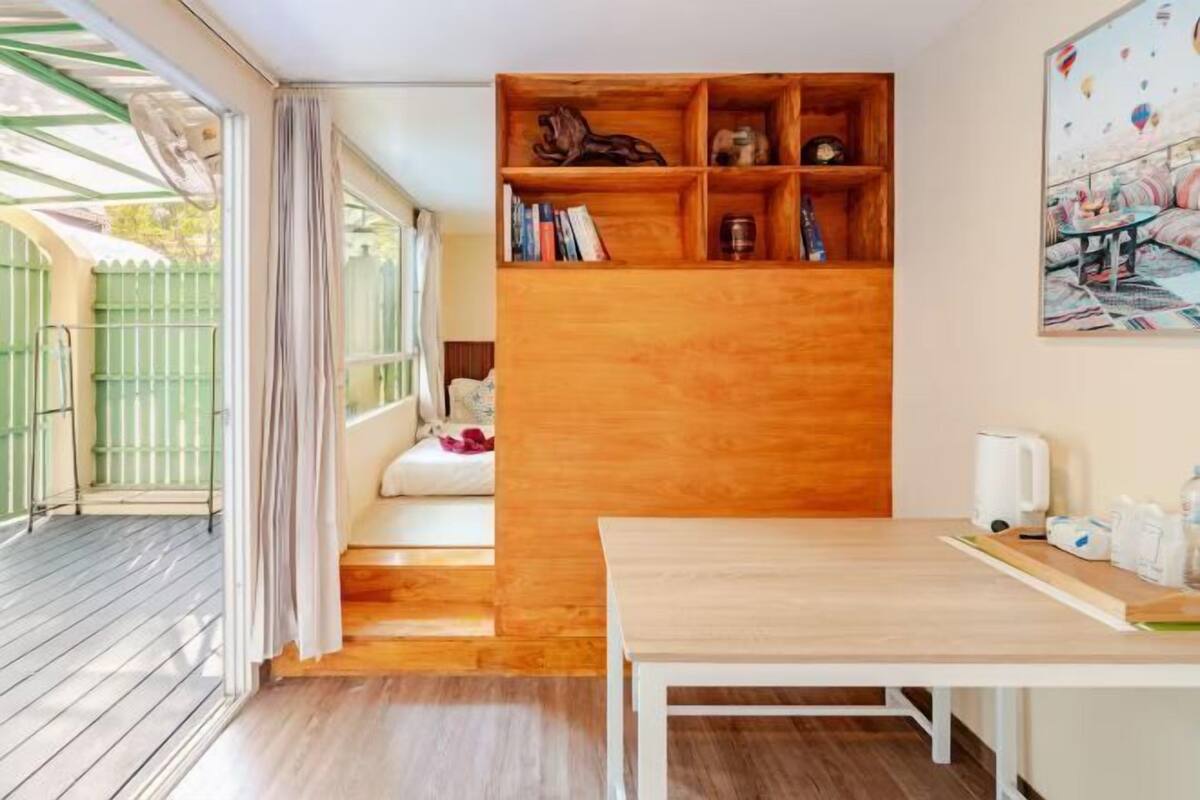 A room with a wooden bookshelf, a white table, and a window with curtains.