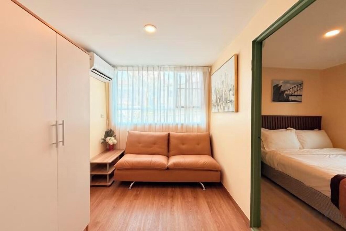 A compact room with a sofa, a bed, and a wardrobe.