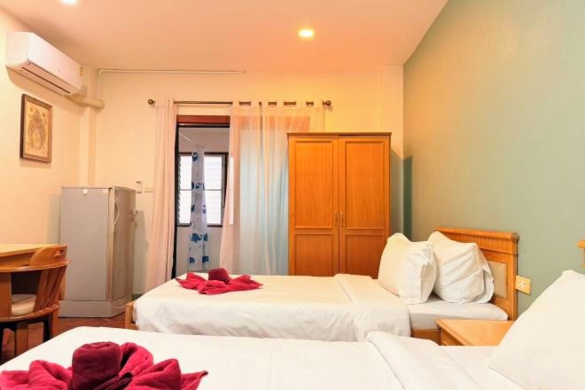 Une chambre d’hôtel avec deux lits, un bureau, une armoire et un appareil de climatisation.