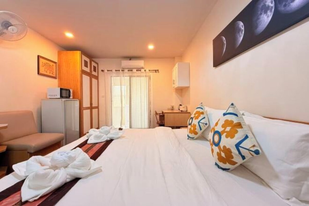 Une chambre d’hôtel équipée d’un lit, d’un bureau, d’une chaise, d’un four à micro-ondes et d’un ventilateur.