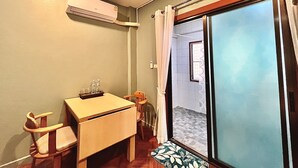 Une petite pièce comprenant un bureau, une chaise et un appareil de climatisation fixé au mur.