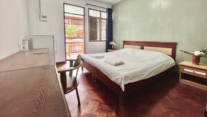 Une chambre à coucher avec un lit, un bureau et une chaise. Il y a une fenêtre donnant sur un balcon.