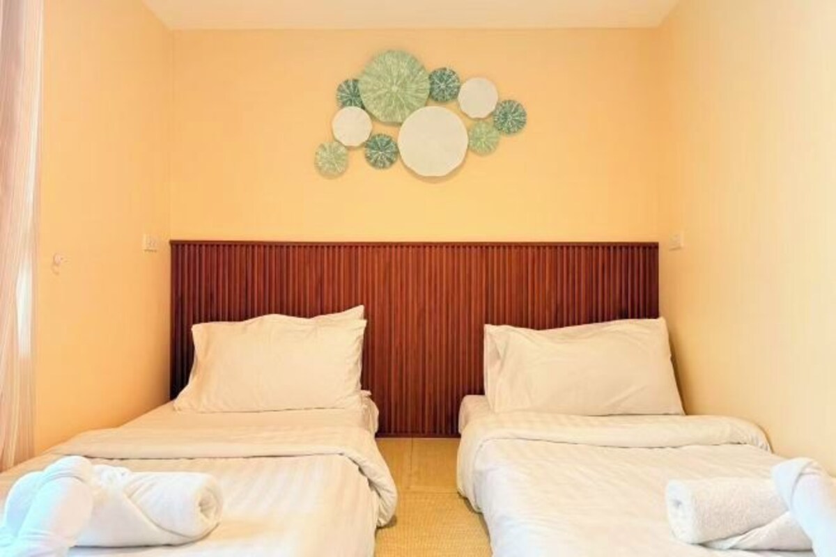 Une chambre d’hôtel avec deux lits, une tête de lit en bois et un élément décoratif mural.